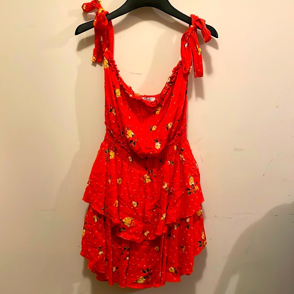 Adorable Romper in coral with floral accents and ruffled skirt.  Tie shoulders.